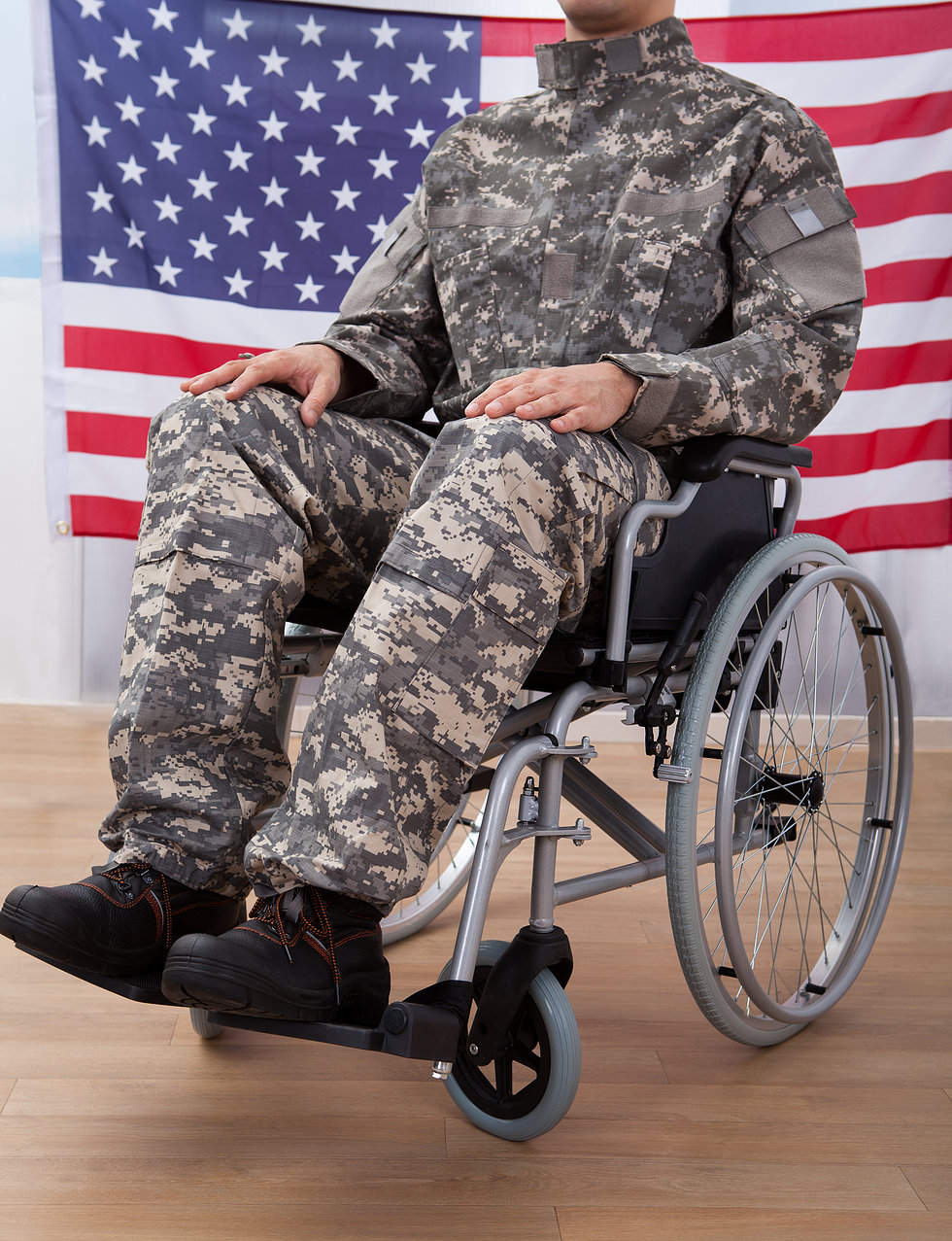 Patriotic Soldier Sitting On Wheel Chair Against American Flag Financial Assistance for Veterans in Texas